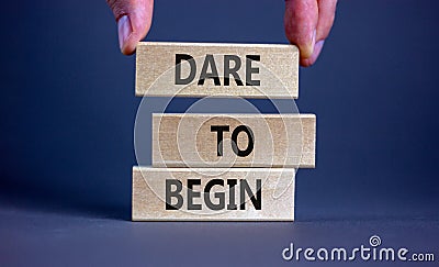 Dare to begin symbol. Wooden blocks with words `Dare to begin`. Beautiful grey background, businessman hand. Business, dare to Stock Photo