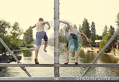 Daring young boys jumping off a bridge into the river. View from behind. Stock Photo