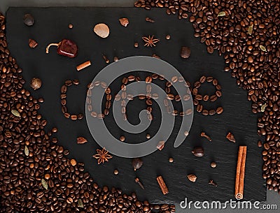 Dark background with coffeeped phrase Coffe. Black texturised background with coffee beans and spices. Stock Photo