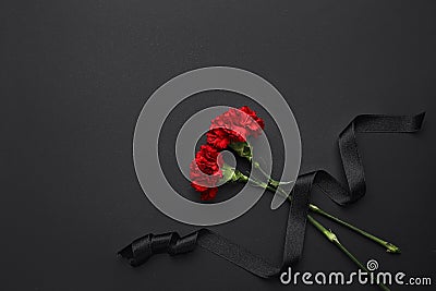 Black funeral ribbon with carnation flowers on dark background Stock Photo