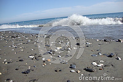 Dark beach with stones and wave in backgroun Stock Photo