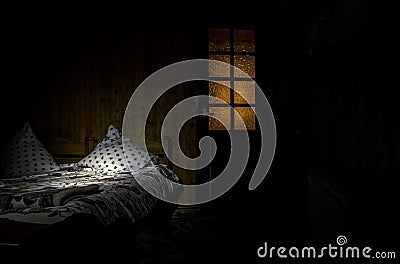 Dark bedroom with bed and pillows surreal lights and wooden door with window. Stock Photo