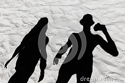 Dark black silhouette of a guy and a girl shade on a white beach sand background Stock Photo