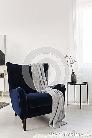 Dark blue velvet wing back chair with grey blanket in trendy living room Stock Photo