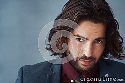 Dark and brooding good looks. Studio shot of a handsome and dapper young man posing against a grey background. Stock Photo