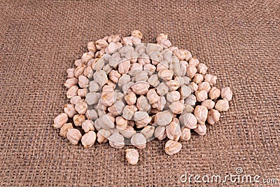 dark brown burlap fabric on which are shown the seeds of Turkish peas stacked in one heap Stock Photo