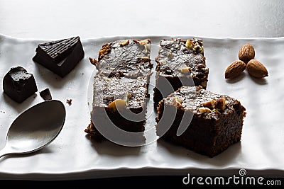 Dark Chocolate almond brownies served on a white ceramic plate with dark wooden background. Stock Photo