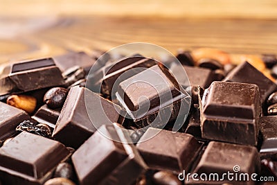 Dark chocolate cubes, coffee beans, peanuts and raisins on wooden table, close-up Stock Photo