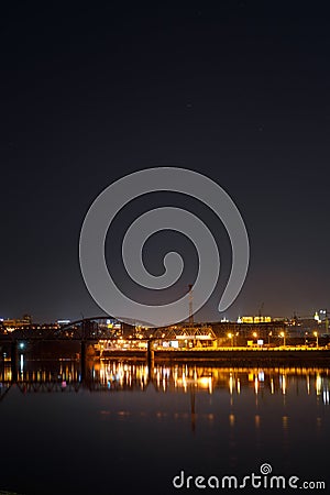 Dark cityscape with buildings, lights, river Stock Photo