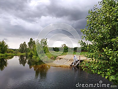 Dark cloudy storm river view. Woman on the pier Stock Photo