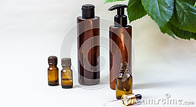 Dark cosmetic bottles and green natural leaves on a light background. Copy space Beauty salon blogger, salon therapy, minimalist Stock Photo