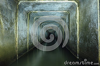 Dark and creepy flooded underground sewer concrete tunnel. Industrial wastewater and urban sewage flowing throw the tunnel Stock Photo