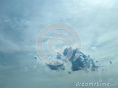 Dark cumulonimbus cloud amongst cirrus clouds in gray/blue sky. Stock Photo