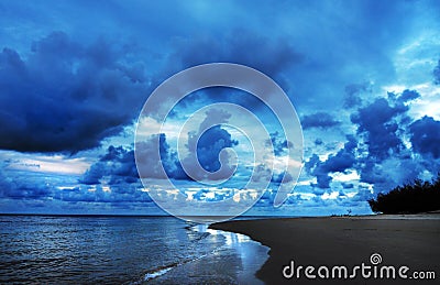 Dark dangerous tropical storm clouds rolling in sky over ocean coastal beach Stock Photo