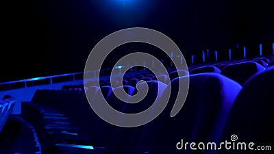Dark, empty cinema hall with comfortable seats in blue light. Close up for seat rows in movie theatre. Stock Photo