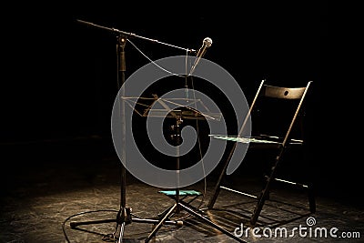 Dark empty room with a microphone and a chair on a stage Stock Photo