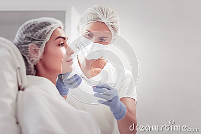 Dark-eyed female cosmetologist providing mesotherapy for woman Stock Photo