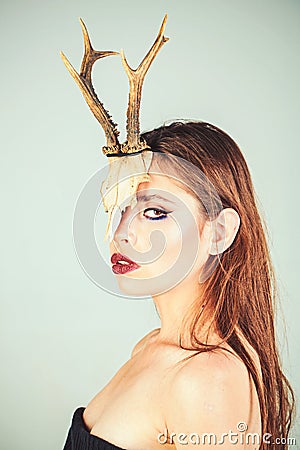 Dark fantasy creature elf on halloween in skull. Woman with makeup and antlers. Fashion devil of mystic shaman girl with Stock Photo