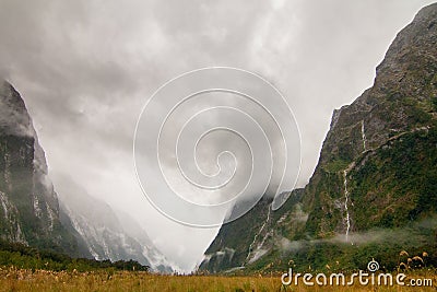 Dark and foggy Fiordland valley, water falls from misty mountains, Milford Track New Zealand Stock Photo