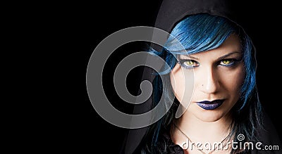 Dark girl with yellow cats eyes, blue hair and black hood Stock Photo