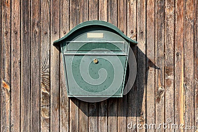 Dark green metal vintage retro mailbox with lock mounted on wooden boards barn wall Stock Photo
