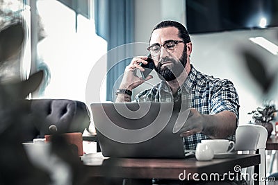 Dark-haired freelance writer calling his colleague working remotely Stock Photo