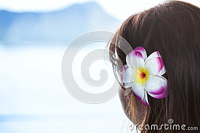 Dark haired girl wearing Hawaiian flower looking at ocean view Stock Photo