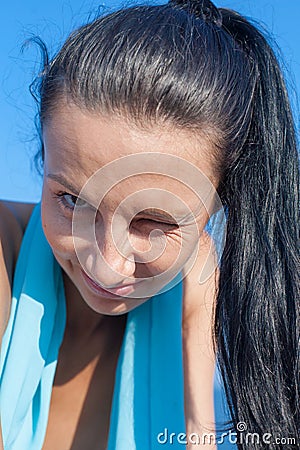 Dark haired person with ponytail looks at camera and winks Stock Photo