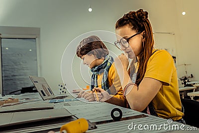 Dark-haired schoolgirl using her imagination while drawing sketches Stock Photo