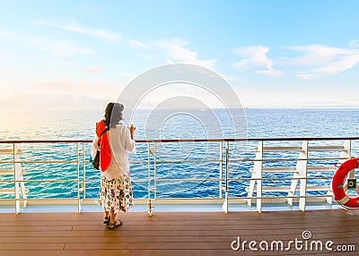 A dark haired woman on enjoys a drink on the deck of a cruise ship passing through the Greek Islands at sunset Editorial Stock Photo