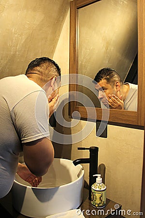 Dark-haired 40-year-old Latino man does his beauty routine, shaves with shaving cream and soap to avoid folliculitis Stock Photo