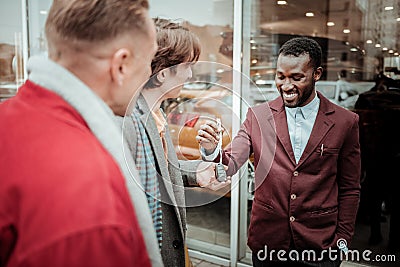 Dark-haired young man taking car keys form smiling sales consultant Stock Photo