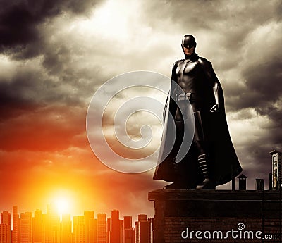 Dark Superhero on rooftop overlooking cityscape Stock Photo