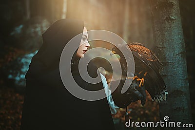 Dark hooded woman and hawk Stock Photo