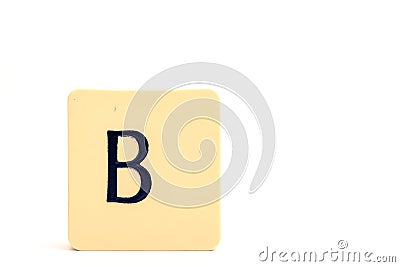 Dark letter B on a pale yellow square block isolated on white background Stock Photo