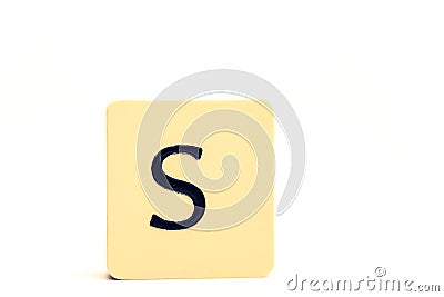 Dark letter S on a pale yellow square block isolated on white background Stock Photo
