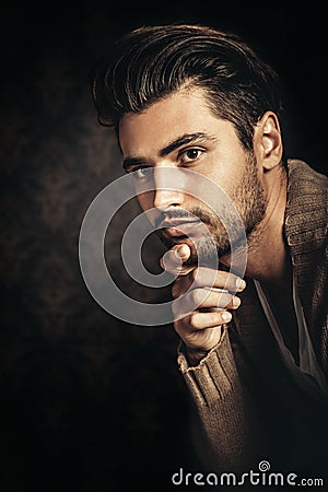 Dark light portrait of a young handsome man, hand under his chin. Stock Photo