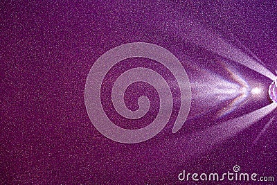 On a dark lilac structural fine-grained background, a light purple scattered beam of light Stock Photo