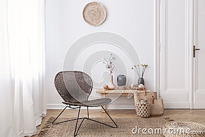 Dark, modern wicker chair in a white living room interior with a wooden bench and decorations made from natural materials Stock Photo