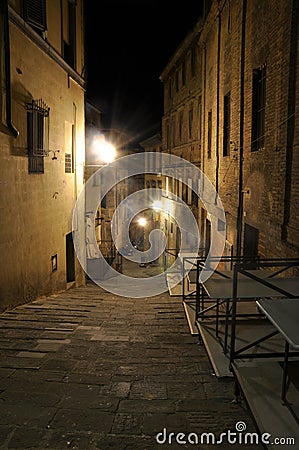 Dark narrow alley with old buildings and street lamps in Siena,Tuscany Stock Photo