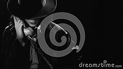 Dark noir portrait of a female detective holding a retro telephone receiver. Private detective, spy, investigation Stock Photo