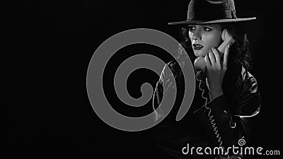 Dark noir portrait of a female detective holding a retro telephone receiver. Private detective, spy, investigation Stock Photo