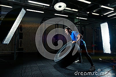 Dark photo of a strong bodybuilder with a heavy wheel Stock Photo