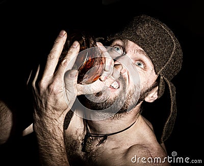 Dark portrait of scary evil sinister bearded man with smirk, holding a bottle of cognac. strange Russian man with a Stock Photo