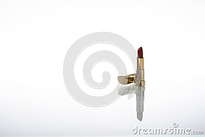 Dark red lipstick with golden housing with reflection on glass isolated on white background Stock Photo