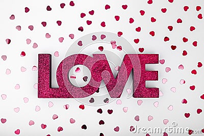 Dark red sign LOVE and glitter heart confetti. Valentine day concept. Trendy minimalistic flat lay design background Stock Photo