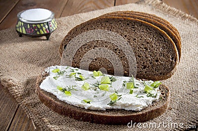 Dark rye bread, sandwich with cream, chives and dill and salt in saltshaker on burlap. Close-up Stock Photo