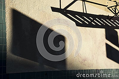 Dark shadows of fire escape and sign on side of stucco building Stock Photo