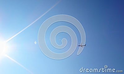 Dark silhouette of airplane flying over the blue skies and sun r Stock Photo