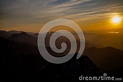 Dark silhouettes of the Carpathian rocky mountains and sunset sky with a large yellow sun Stock Photo